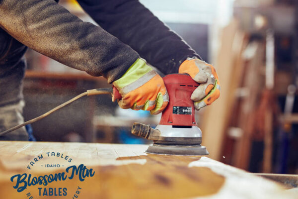 Male carpenter using orbital electric sander in a retro vintage workshop.